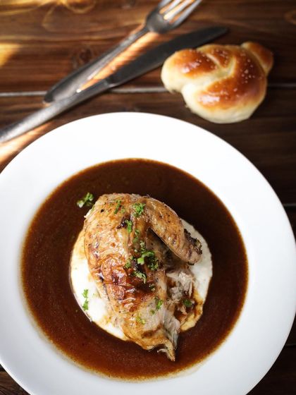 A beautifully plated roasted chicken served on a bed of creamy mashed potatoes with a rich pan sauce. This is the kind of elegant dish you can learn to master.