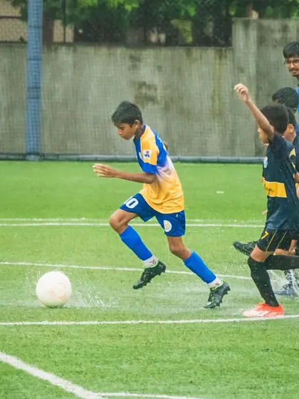 A young player from our U13 team dribbling through a water-logged pitch during a league game.