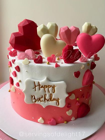 A cake overflowing with love, decorated with pink and red chocolate hearts in various sizes and textures. Perfect for a birthday or anniversary.