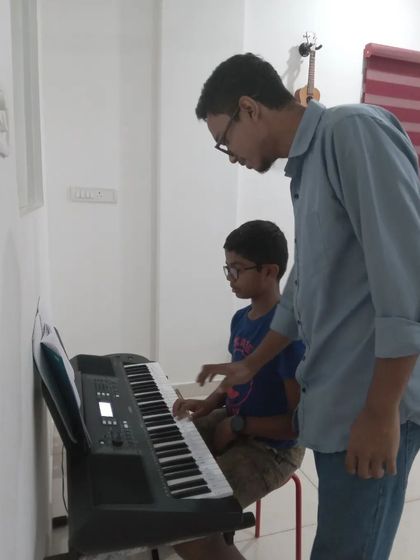 An instructor guiding a young student's hands on the keyboard. We make learning accessible and fun for our youngest musicians.