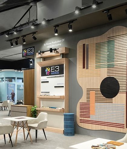 A large, artistic wall installation made from the client's laminate products serves as a major focal point in the E3 exhibition space. This piece demonstrates the creative possibilities of the material in a visually compelling way.