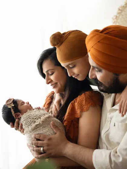 A side profile of a family looking lovingly at their newborn baby. The soft, natural light from the window creates a serene atmosphere for this lifestyle family photoshoot.