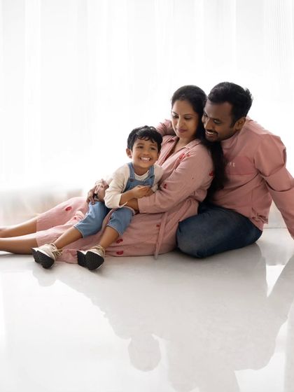 A relaxed and loving family portrait on the floor. The reflection on the glossy floor adds a beautiful artistic touch.