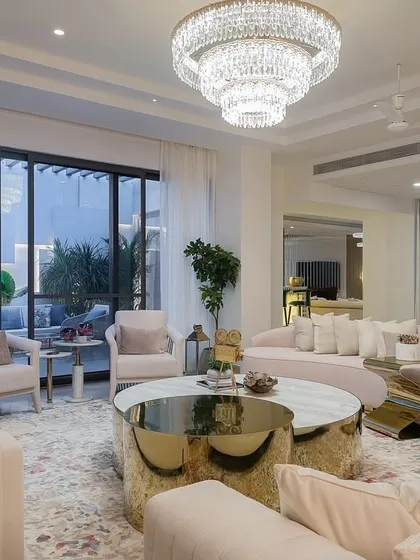 Inspired by American contemporary design, this Chennai living room features a soft blush sofa that curves elegantly through the space. Brass-accented coffee tables and a grand chandelier add a touch of opulence, creating a room that is both impressive and warm.