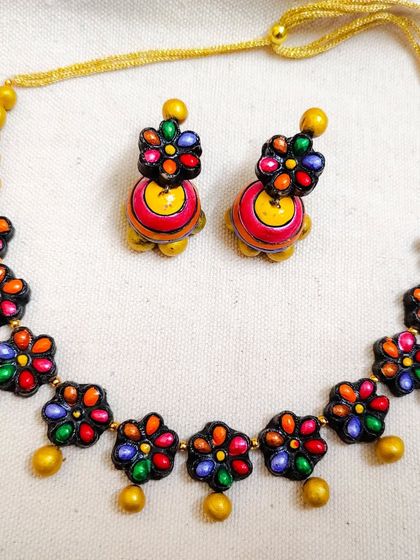 This necklace features multi-colored stone-look alike flowers on a simple chain. It's a sleek and colorful piece that comes with beautiful matching jhumka earrings.