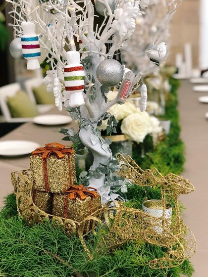 Detailed view of the Christmas centerpiece, highlighting the textures of the golden wire reindeer and sparkling gift decorations nestled in the greenery.