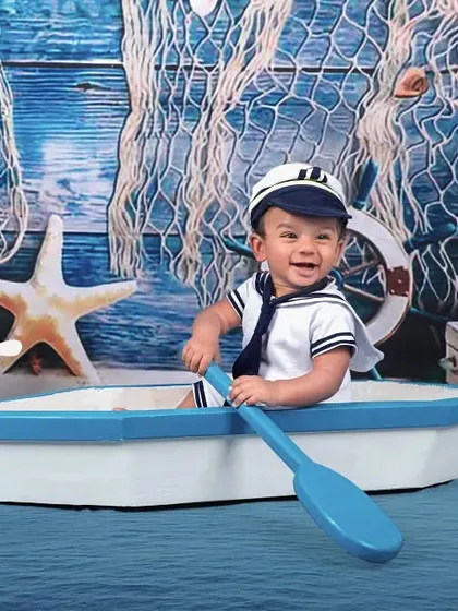 All aboard! This little sailor is ready to set sail in our adorable nautical-themed studio setup, complete with a sailor suit, boat, and anchor.