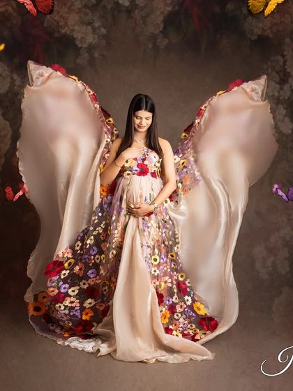 To add a touch of magic, I can incorporate fantasy elements like these fluttering butterflies. They surround the mother-to-be, who is wearing a beautiful floral gown with fabric wings.