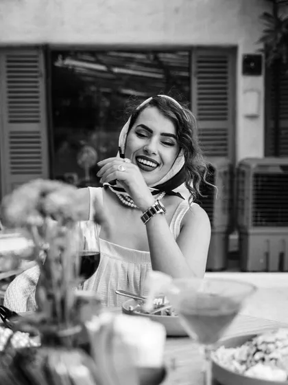 A black and white portrait capturing a moment of laughter at an outdoor cafe. The monochrome treatment adds a timeless, classic feel to this lifestyle image.