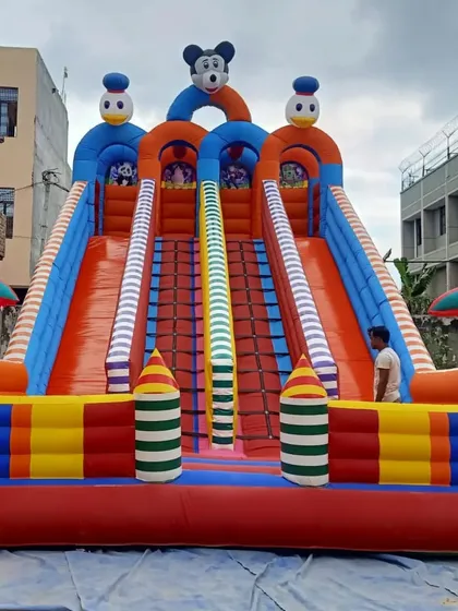 A large 4-slider bouncy castle with a tall structure, perfect for making an impact at events. The striped pillars and character art add to its visual appeal.