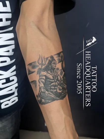 A detailed armband tattoo featuring Lord Shiva in a meditative pose, set against the backdrop of Mount Kailash.