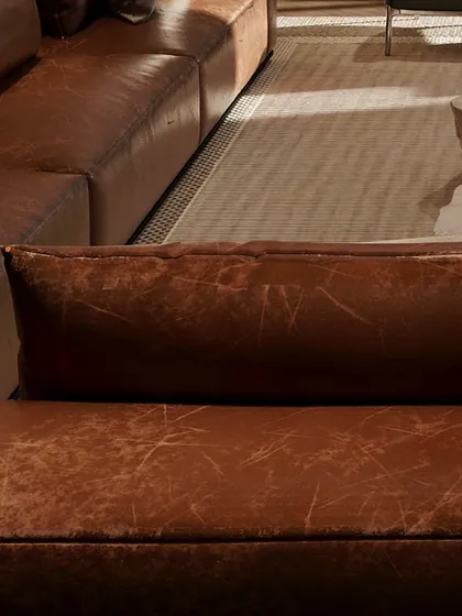 A close-up of the distressed leather sofa, showcasing the beauty of natural materials. The texture adds a layer of warmth and character to this leisure space.