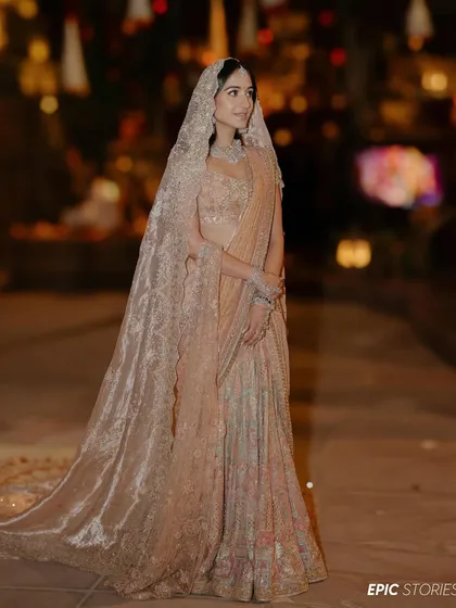 A full-length portrait of Radhika in her breathtaking Tarun Tahiliani lehenga. The delicate lacework and the long, flowing veil created an ethereal and unforgettable bridal look.