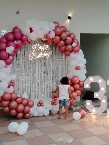 This is another example of a grand birthday backdrop, perfect for photos. I designed this circular arch with rose gold and white balloons, a silver shimmer curtain, a neon sign, and large light-up numbers for a 31st birthday.