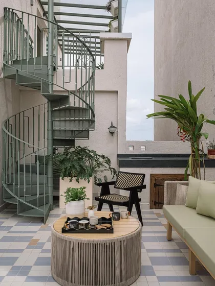 A spiral staircase on the outdoor deck leads up to the master bedroom. The verdant color palette and lush greenery enhance the feeling of being in a garden oasis.