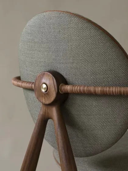 A detail shot of the back of the inspirational chair, highlighting the fine craftsmanship where the wood, metal, and fabric components meet. The wrapped armrest adds a beautiful textural element.