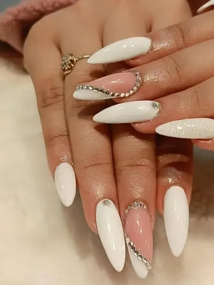An elegant combination of solid white and sheer pink nails on an almond shape, accented with delicate lines of rhinestones for a touch of class.