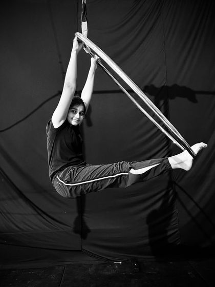 This black and white photo shows a student holding a strong "L-sit" inside the hoop, a challenging move that builds immense core strength.