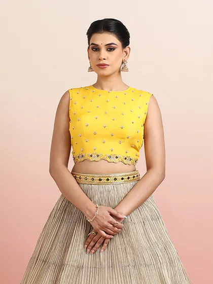 A close-up of the yellow blouse paired with the beige paisley lehenga, showing the intricate details of both pieces.