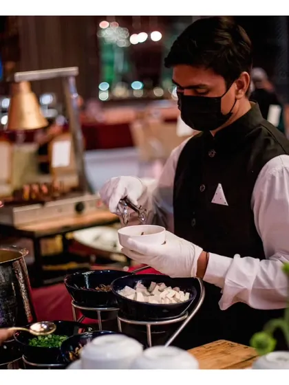 A server assembles a bowl with various toppings at a live station. This shows that our live concepts extend beyond cooking to include customizable bowls and salads, catering to diverse preferences.