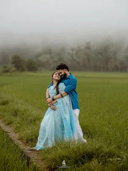A warm embrace in a vibrant green paddy field. The misty background adds a dreamy, romantic quality to this pre-wedding photo.