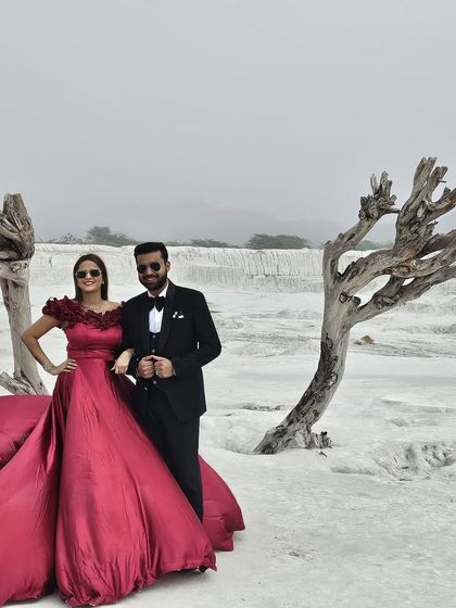 Our crimson trail gown in action during a pre-wedding shoot. This image shows how the gown contrasts stunningly against a stark landscape, creating a powerful and romantic visual.