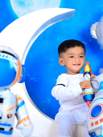 A smiling little astronaut ready for a space adventure, surrounded by planets and rockets.