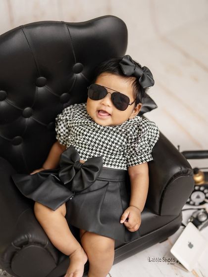 This little boss lady means business! With her sunglasses on and a confident pose, she's ready to take on the world in this stylish themed shoot.