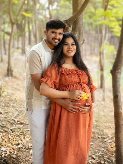A classic couple's portrait against a backdrop of trees. Their gentle smiles and close embrace convey the love and excitement of this special time.