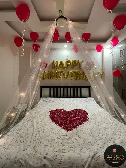 This view shows the full "HAPPY ANNIVERSARY" foil balloon message above the decorated bed.
