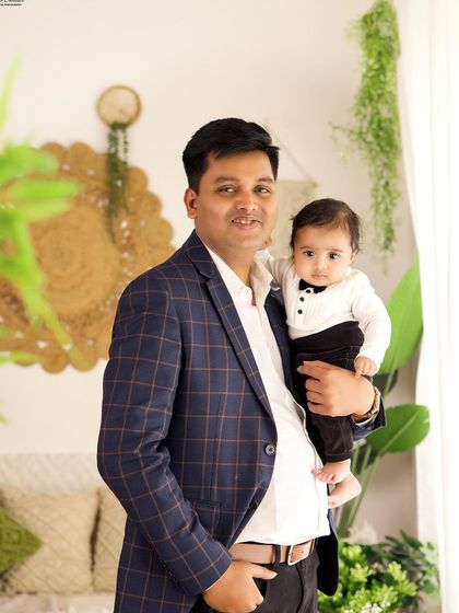 A proud father holding his dapper son, who is dressed in a cute little tuxedo shirt. A sweet portrait from a family milestone session.