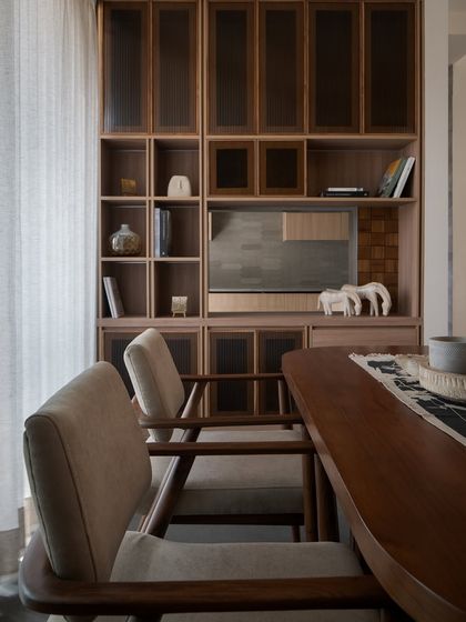 The interior palette is inspired by Japanese sensibilities, with warm wood, muted textures, and tactile finishes. Custom shelving and simple upholstery create a space that feels composed and lived-in.
