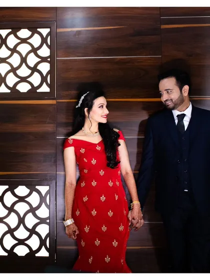 A classic and elegant portrait of the couple holding hands. The bride's stunning red dress and the groom's sharp suit make for a timeless photo.