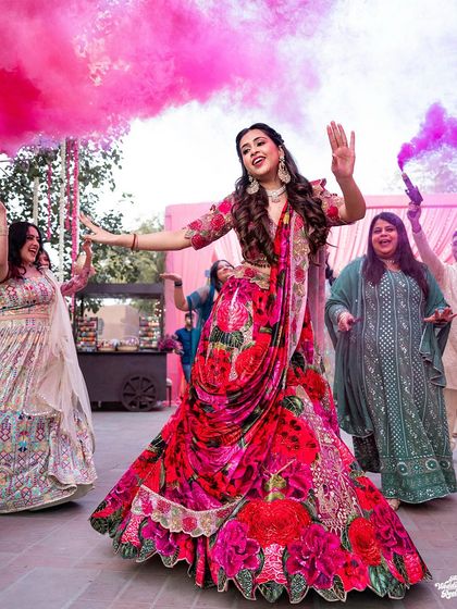 The bride's grand entrance for her Sangeet performance, surrounded by friends and pink smoke.