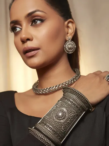 This shot focuses on the stunning silver cuff and the model's flawless profile. The makeup is subtle yet effective, defining her features without overpowering the product.