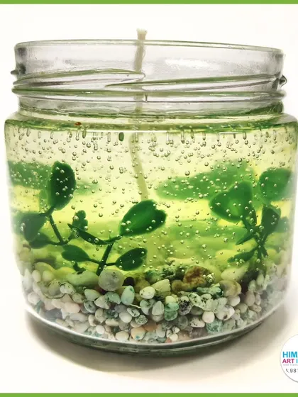 A green gel candle with embedded pebbles and plant-like structures, creating a mini terrarium effect.