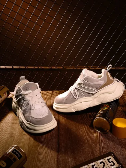 A lifestyle-oriented shot of sneakers in a rustic, urban setting with spray paint cans. This styling tells a story of street art and culture, connecting the product to a specific subculture.