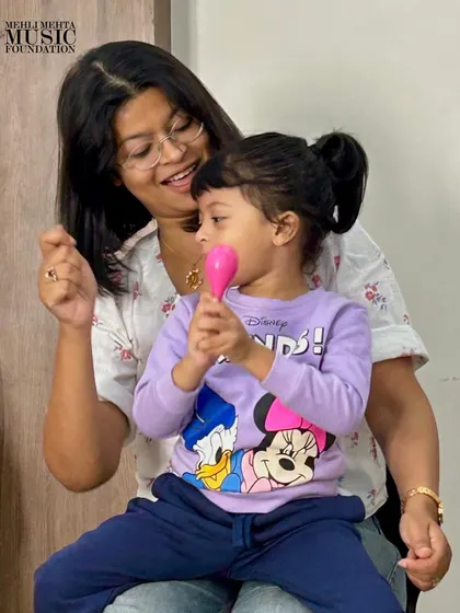 Our early-years certification covers teaching even the youngest learners. This photo shows a teacher guiding a toddler with a maraca, demonstrating how we create a nurturing musical bond between the instructor, the child, and sometimes the parent, right from the start.