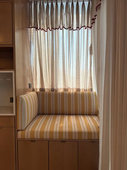 I'm obsessed with the little details in my studio, like this cozy reading nook with its striped yellow cushions and custom curtains. It's the perfect spot for a bit of quiet inspiration.