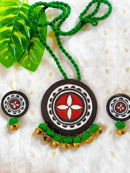 A variation of my ghungroo-embellished mandala set, this piece uses a striking green and red color scheme. The hand-painted pendant is complemented by a braided green cord and matching earrings. The brass bells add a touch of traditional charm to the design.