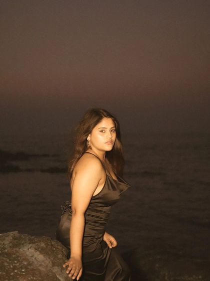 A similar low-light shot from the same evening beach session. The focus is entirely on the subject's expression, with the dark ocean providing a minimal and mysterious background.