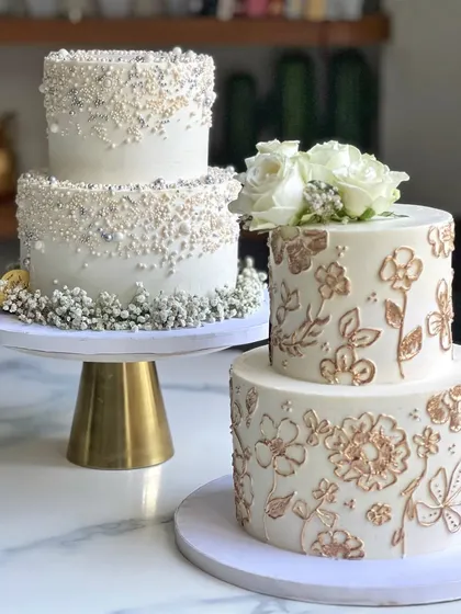 Here are two beautiful options for an intimate white wedding. One features delicate hand-piped and gold-painted floral details, while the other is adorned with a cascade of sparkling sprinkles. Both are 3.5 kilos and completely eggless.