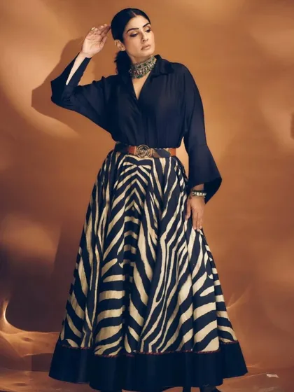 A powerful pose from Raveena Tandon. The clean, center-parted hairstyle emphasizes her strong features and adds a touch of severity to this high-fashion look.