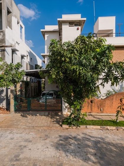 The Samvrruddhi home, designed to feel like a farmhouse in the city. The exterior features a unique, sculptural mud wall at the entrance, immediately signaling the home's connection to the earth.