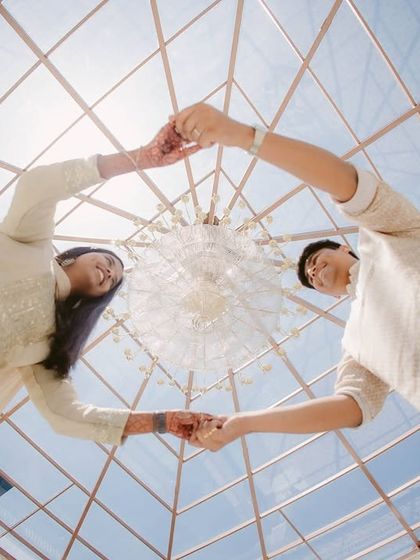 A creative low-angle shot of a couple forming a heart with their hands under a glass ceiling. It's a playful and unique perspective on their connection.