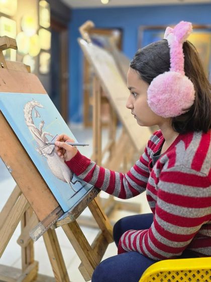 A young artist with fuzzy earmuffs stays warm and focused while working on her imaginative ballpoint pen drawing. We ensure our studio is a comfortable space for creativity.