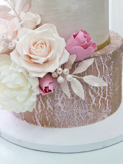 A close-up of the handcrafted sugar flowers and delicate wafer paper leaves on the 50th anniversary cake. Each petal is individually shaped and dusted to create a realistic, beautiful arrangement.