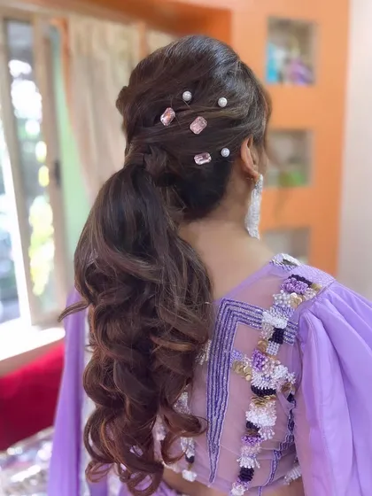 A messy ponytail adorned with pink crystals and pearls, a glamorous and unique look.