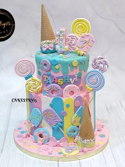 This two-tier Candyland-themed cake is a pastel dream. Created for a first birthday, it's covered in fondant lollipops, donuts, and ice cream cones for a super sweet celebration.