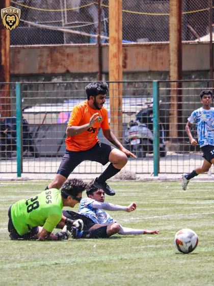An SG5 player skillfully evading a slide tackle during a First Division match. Quick thinking and agility are key.